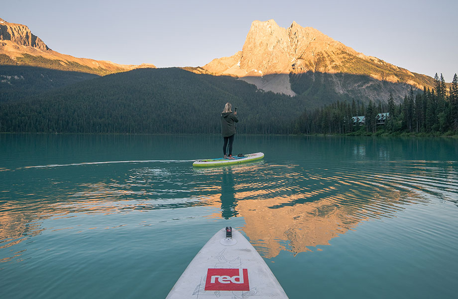 girl paddles with mountains on the horizon