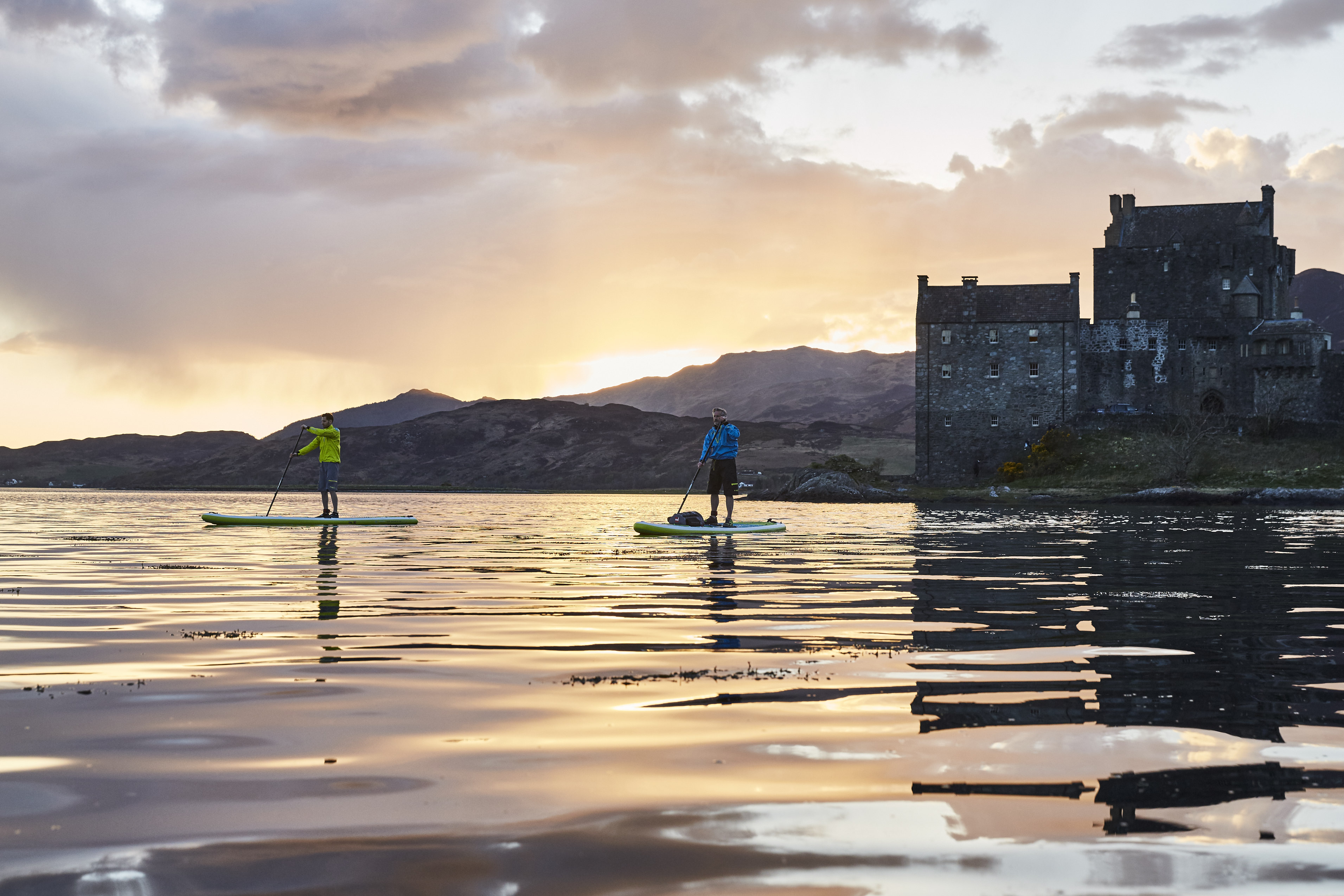 two paddle boarders on a Scottish loch at sunset 