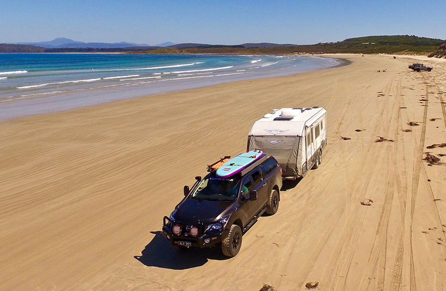 4x4 towing a caravan with a paddle bourdon roof on the beach