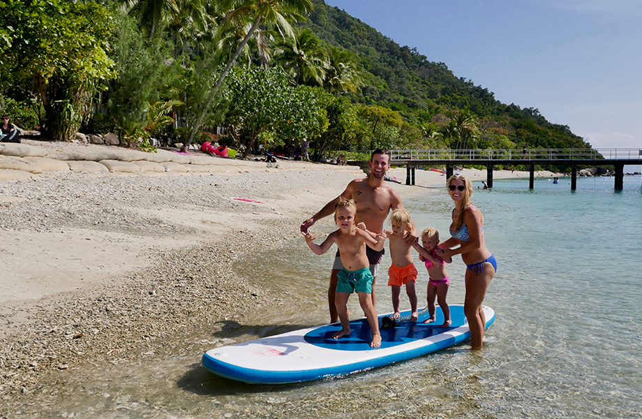 Family stood on paddle board in the shallow water