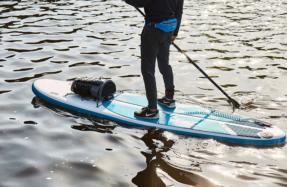 paddle boarder wears PFD and leash for safety on SUP