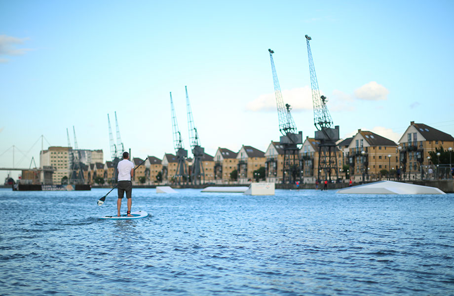 Man stands looking at city skyline on paddle board