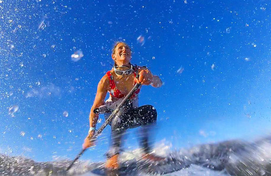 close up of woman smiling as she catches a wave with her paddle board
