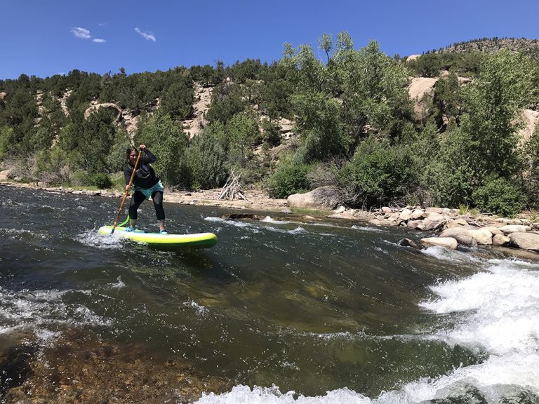 Woman paddles white water in Aspen Colorado